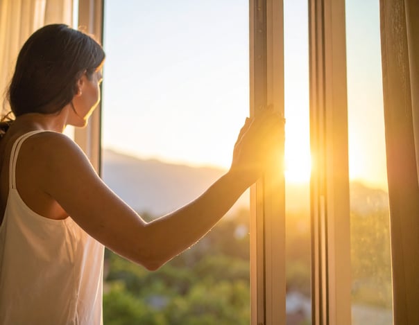 Firefly_foto de una mujer abriendo una ventana y en el fondo se ven los primeros rayos del so 643949